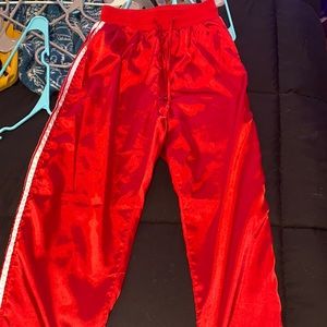 Red satin track pants with two white stripes on each side